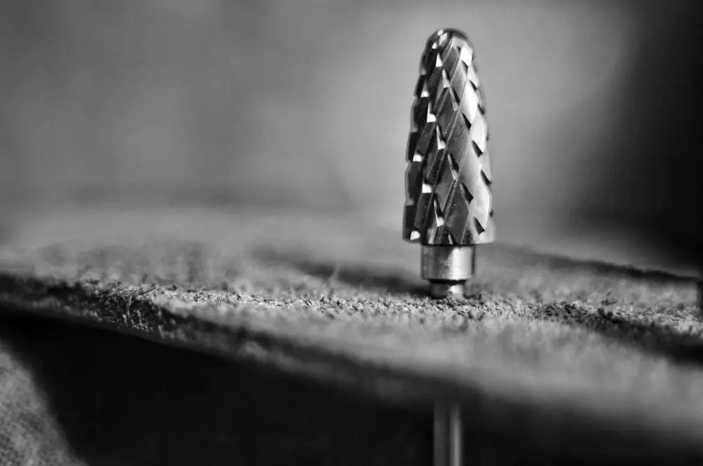 Close-up of a drill bit on a textured surface with a blurred background